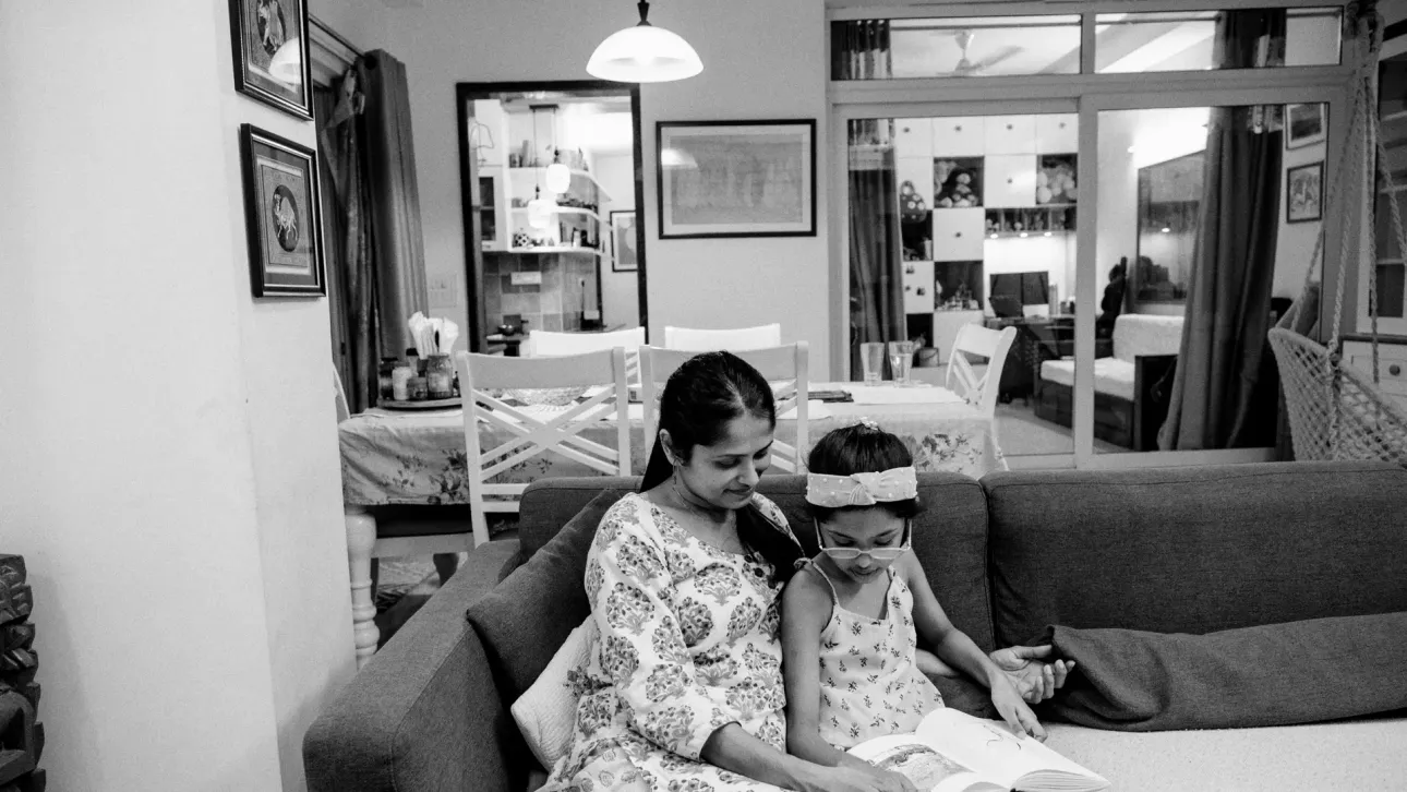 Woman and her seven-year-old daughter reading a book together.