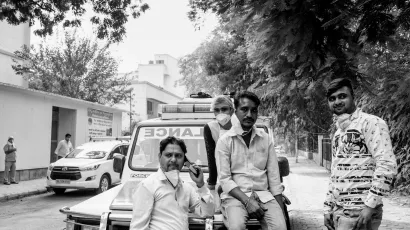 Team of young Covid-19 ambulance drivers standing in front of an ambulance