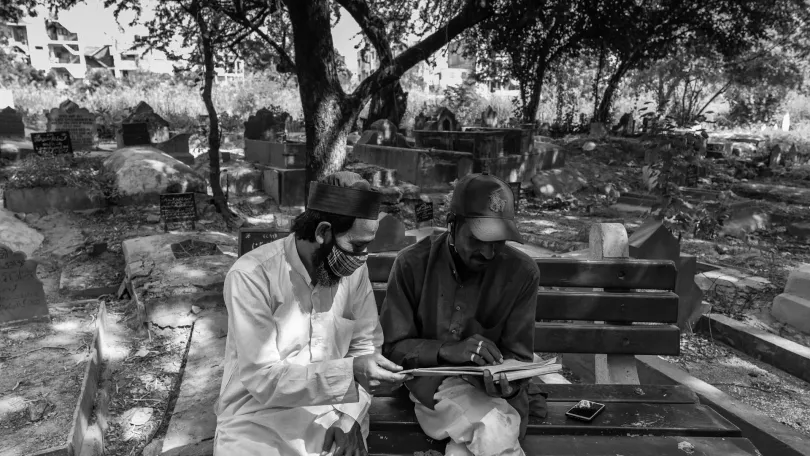 Two cemetery workers review the cemetery’s Covid-19 burial register together