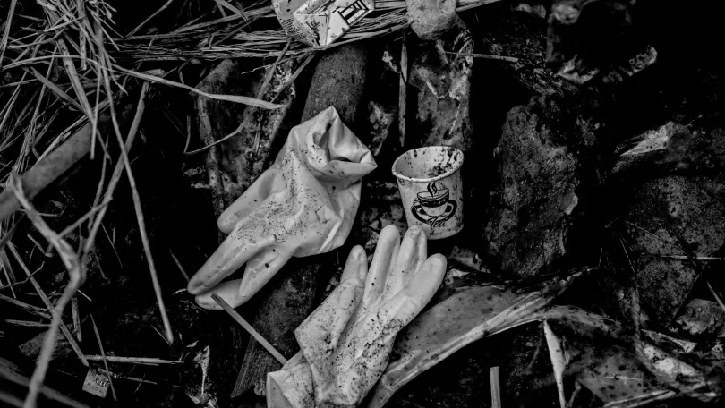 Discarded medical gloves rest in a trash-filled gutter.